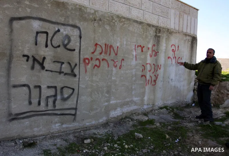 Palestinians look at graffiti sprayed on his house in the West Bank village of El-Jinya near Ramallah, Sunday, Feb. 5, 2012. Palestinians say extremist Jews have scrawled their home in a West Bank village with offensive...