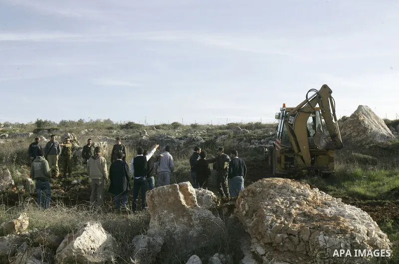 Israeli soldiers stand guards as a bulldozer of the Civil Administration during a demolition in the village of Kufr Qaddum near the Israeli settlement of Kdumim, in the northern West Bank, Sunday, Feb , 05, 2012. Photo b...