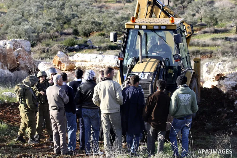 Israeli soldiers stand guards as a bulldozer of the Civil Administration during a demolition in the village of Kufr Qaddum near the Israeli settlement of Kdumim, in the northern West Bank, Sunday, Feb , 05, 2012. Photo b...