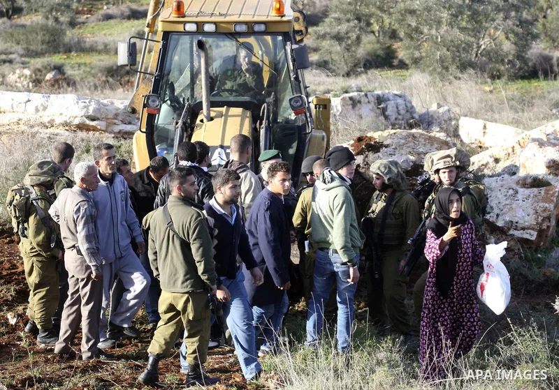 Israeli soldiers stand guards as a bulldozer of the Civil Administration during a demolition in the village of Kufr Qaddum near the Israeli settlement of Kdumim, in the northern West Bank, Sunday, Feb , 05, 2012. Photo b...