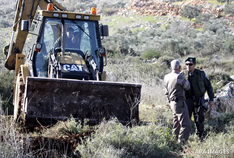 Israeli soldiers stand guards as a bulldozer of the Civil Administration during a demolition in the village of Kufr Qaddum near the Israeli settlement of Kdumim, in the northern West Bank, Sunday, Feb , 05, 2012. Photo b...