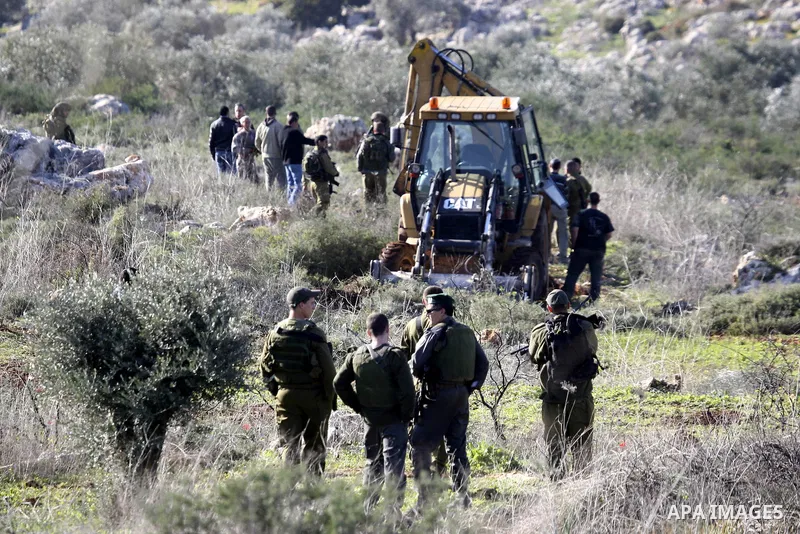 Israeli soldiers stand guards as a bulldozer of the Civil Administration during a demolition in the village of Kufr Qaddum near the Israeli settlement of Kdumim, in the northern West Bank, Sunday, Feb , 05, 2012. Photo b...