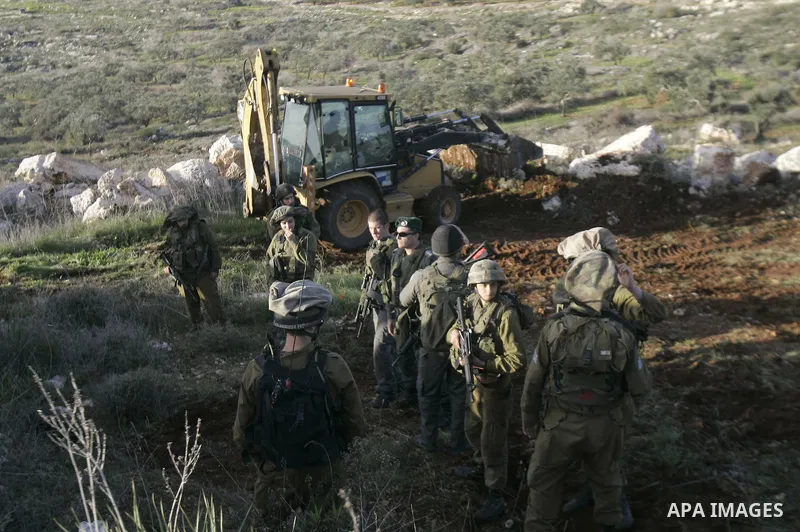 Israeli soldiers stand guards as a bulldozer of the Civil Administration during a demolition in the village of Kufr Qaddum near the Israeli settlement of Kdumim, in the northern West Bank, Sunday, Feb , 05, 2012. Photo b...