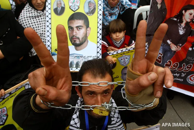 Palestinians hold pictures of their prisoned relatives in Israeli jails as they gather in a weekly activity calling for their liberty at the Red Cross headquarters. 6th February 2012. Photo by Ashraf Amra
