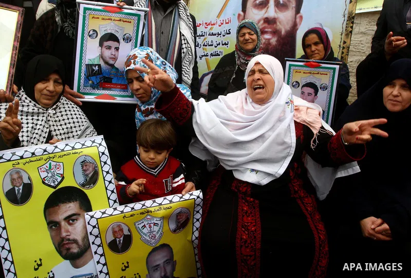 Palestinians hold pictures of their prisoned relatives in Israeli jails as they gather in a weekly activity calling for their liberty at the Red Cross headquarters. 6th February 2012. Photo by Ashraf Amra