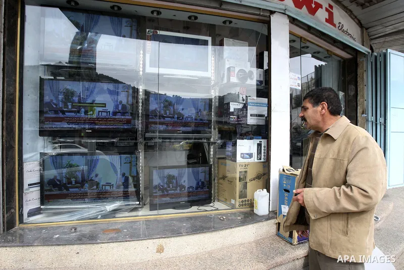 Palestinians watch a television broadcast of Palestinian President Mahmoud Abbas and Hamas leader Khaled Meshaal in Doha, at an appliance store in the West Bank city of Nablus February 6, 2012. Photo by Wagdi Eshtayah