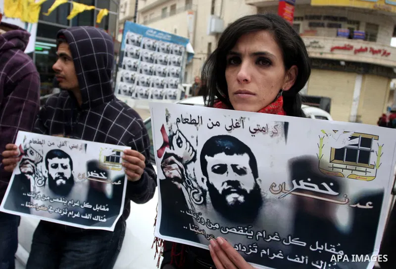 Palestinians hold images of prisoner Khader Adnan, who has been on hunger strike since December 18 while being held in an Israeli jail, during a protest in the West Bank city of Ramallah on February 6, 2012. Adnan, repor...