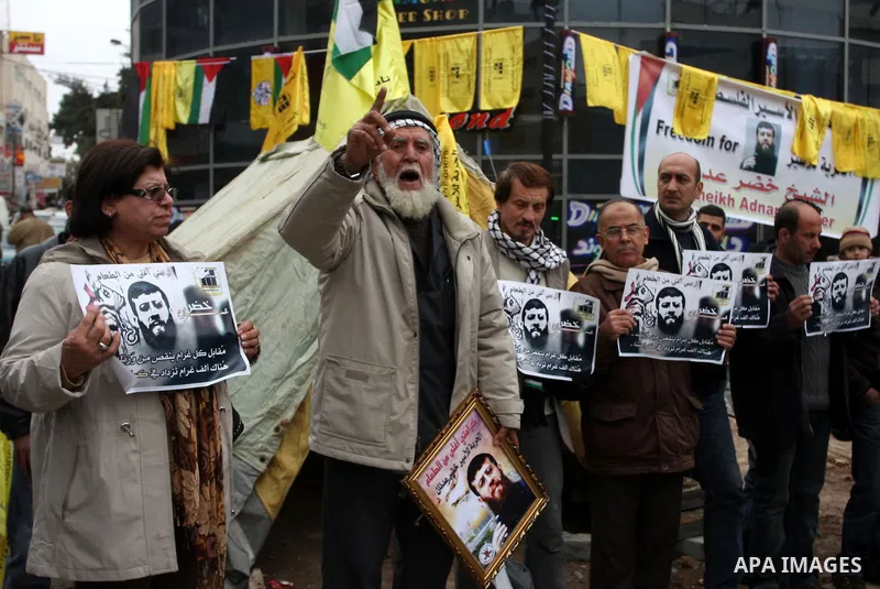Palestinians hold images of prisoner Khader Adnan, who has been on hunger strike since December 18 while being held in an Israeli jail, during a protest in the West Bank city of Ramallah on February 6, 2012. Adnan, repor...