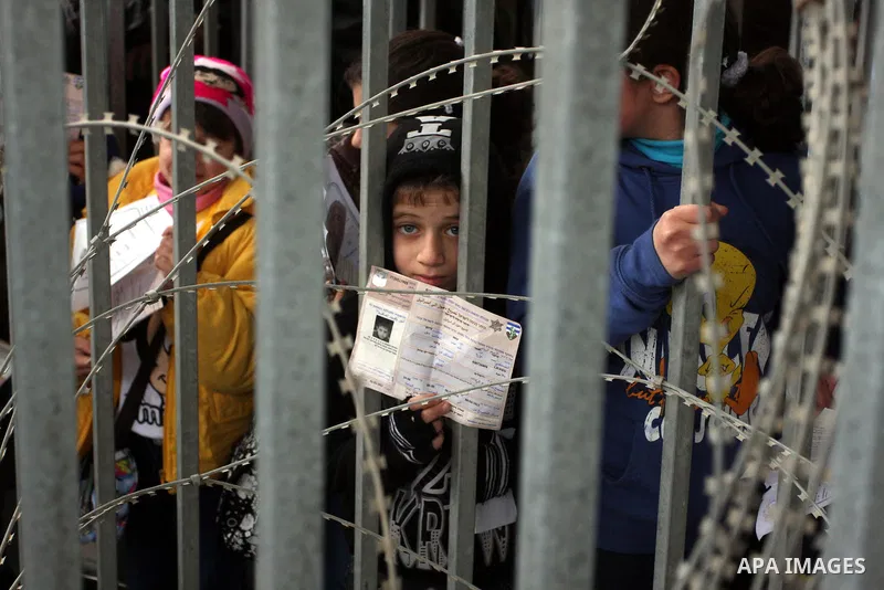 A Palestinian boy holds his permit to enter Israel as he waits at the Qalandia checkpoint between the West Bank city of Ramallah and Jerusalem, Monday, Feb. 6, 2012. Photo by Issam Rimawi