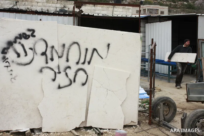 A Palestinian man looks at graffiti sprayed in the West Bank village near Nablus, Feb. 07, 2012. Palestinians say that Jewish extremists had been found on the streets of the village and the man fled, and two Jewish women...