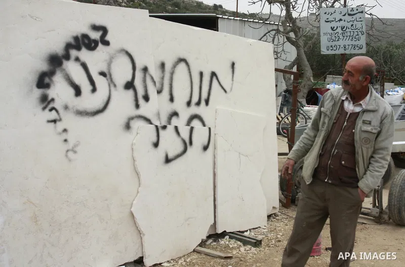 A Palestinian man looks at graffiti sprayed in the West Bank village near Nablus, Feb. 07, 2012. Palestinians say that Jewish extremists had been found on the streets of the village and the man fled, and two Jewish women...