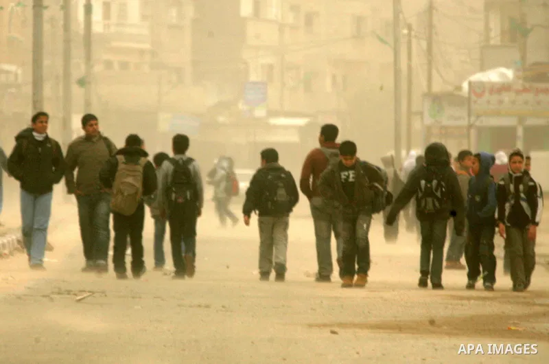 Palestinians walk at a street during cold winds and sand storms in the southern Gaza Strip town of Rafah on February 7, 2012. Photo by Abed Rahim Khatib