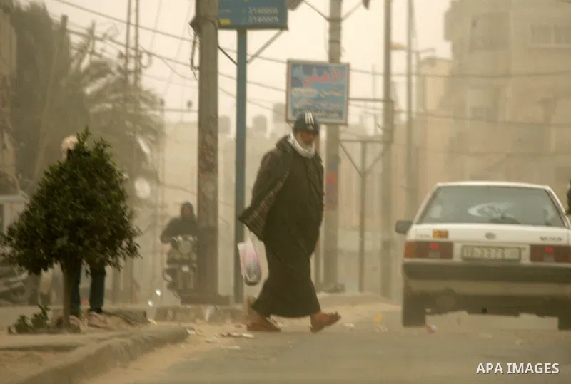 Palestinians walk at a street during cold winds and sand storms in the southern Gaza Strip town of Rafah on February 7, 2012. Photo by Abed Rahim Khatib