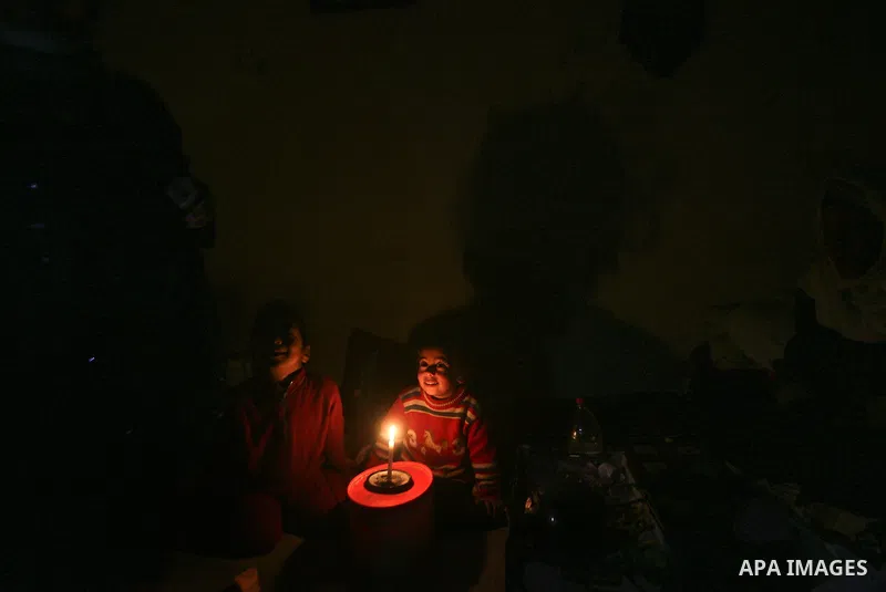 Two Palestinian children playing games on the device at their familiy's home during an electricity power cut in the Jabaliya refugee camp, Gaza Strip, 07 February 2012. Electricity is reported to be cut for 12 hours ever...