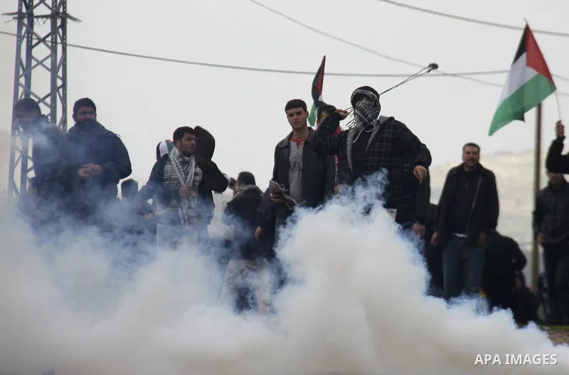 Palestinians protester runs through a cloud of teargas fired by Israeli soldiers during a demonstration against the expropriation of Palestinian land by Israel in the village of Kfar Qaddum, near the West Bank city of Na...