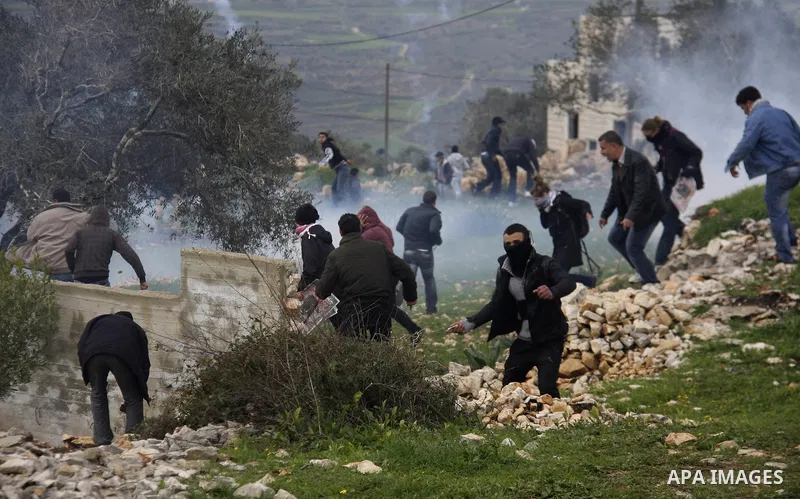 Palestinians protester runs through a cloud of teargas fired by Israeli soldiers during a demonstration against the expropriation of Palestinian land by Israel in the village of Kfar Qaddum, near the West Bank city of Na...