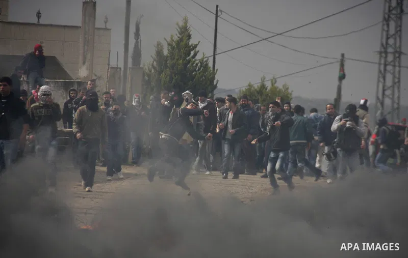 Palestinians protester runs through a cloud of teargas fired by Israeli soldiers during a demonstration against the expropriation of Palestinian land by Israel in the village of Kfar Qaddum, near the West Bank city of Na...