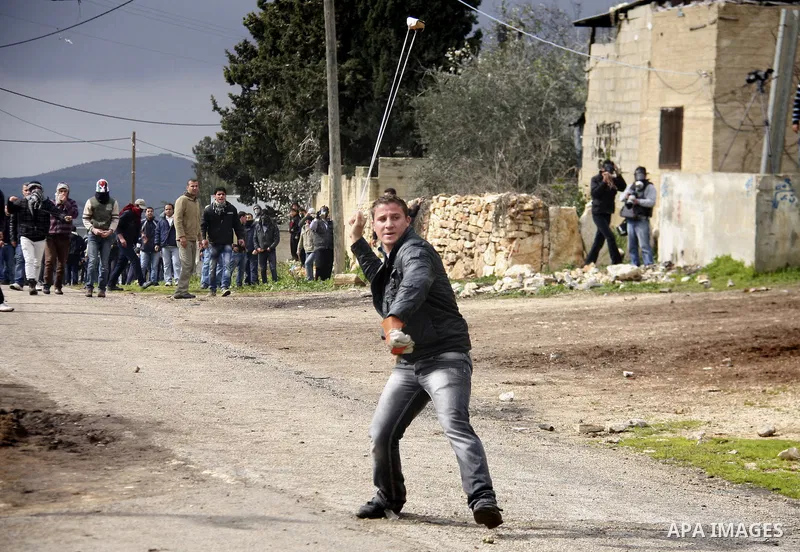 A Palestinian youth hurls a stone at Israeli troops, during a protest in the village of Kufr Qaddum against the expansion of the nearby Jewish settlement of Kdumim, in the northern West Bank, Friday, Feb.10, 2012. Photo...
