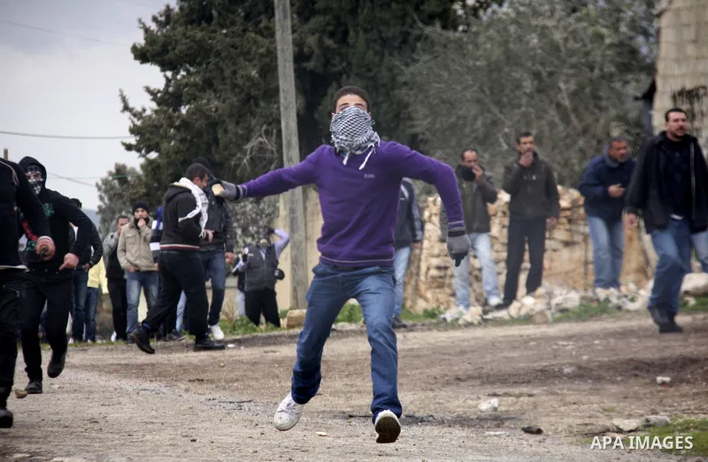 A Palestinian youth hurls a stone at Israeli troops, during a protest in the village of Kufr Qaddum against the expansion of the nearby Jewish settlement of Kdumim, in the northern West Bank, Friday, Feb.10, 2012. Photo...