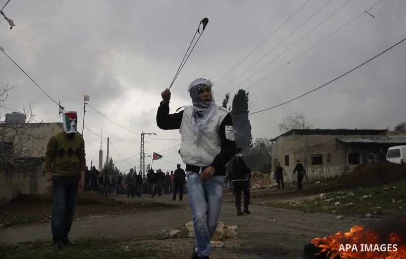 A Palestinian youth hurls a stone at Israeli troops, during a protest in the village of Kufr Qaddum against the expansion of the nearby Jewish settlement of Kdumim, in the northern West Bank, Friday, Feb.10, 2012. Photo...