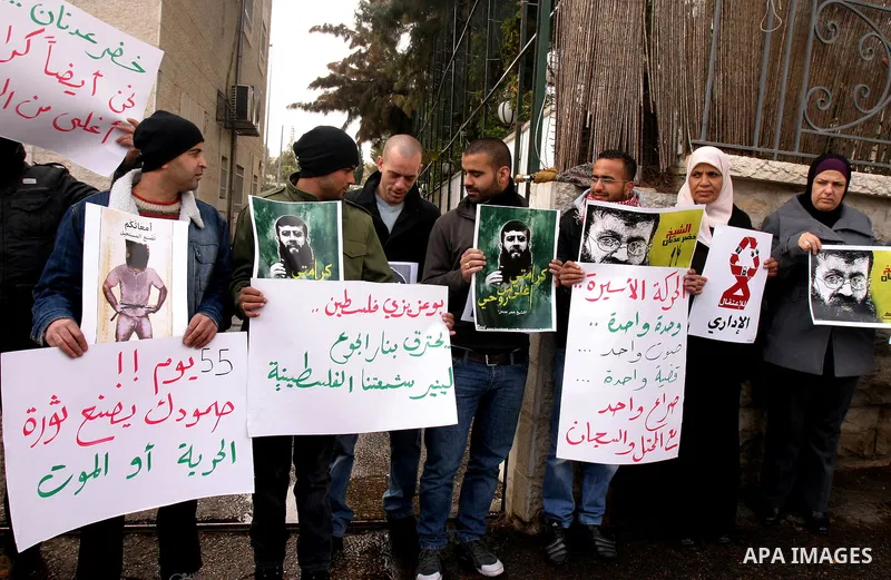 Palestinian protesters shout slogans during a demonstration in support of Khader Adnan (portrait), a Palestinian held in an Israeli prison without trial and who is on hunger strike since December 18, outside the Red Cros...