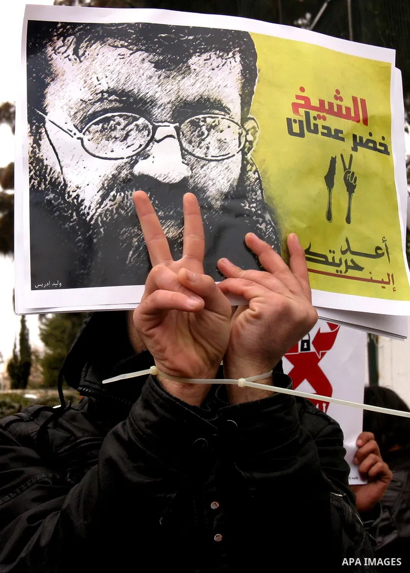 Palestinian protesters shout slogans during a demonstration in support of Khader Adnan (portrait), a Palestinian held in an Israeli prison without trial and who is on hunger strike since December 18, outside the Red Cros...