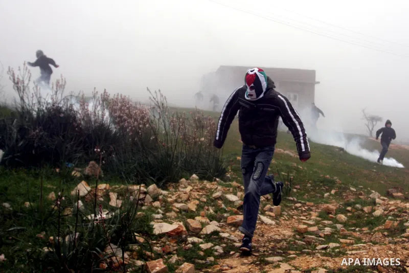 A Palestinian protester hurls stone at Israeli troops during a demonstration against the expansion of the nearby Jewish settlement of Halamish in the West Bank village of Nabi Saleh near Ramallah, Friday, Feb. 10, 2012....