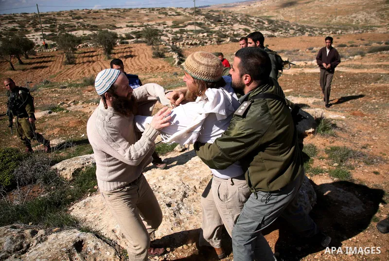 A Jewish settler from the Susia Israeli settlement argues with Israeli soldiers after a donkey was used by Palestinian farmers to transport trees to be planted on their land close to Susia village, in the Israeli occupie...