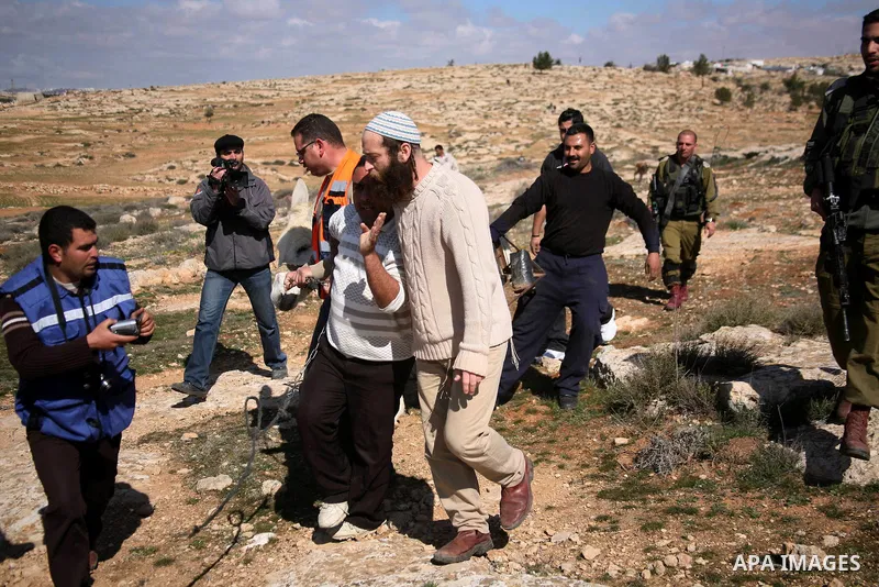 A Jewish settler (c) from the Susia Israeli settlement argues with Israeli soldiers after a donkey was used by Palestinian farmers to transport trees to be planted on their land close to Susia village, in the Israeli occ...