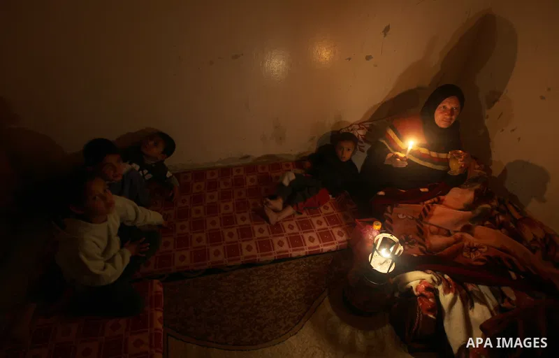 A Palestinian woman and her child sit at their home during a power cut at the Shati refugee camp in Gaza City on February 11, 2012. The Gaza energy authority announced that if fuel doesn't enter the coastal enclave, the...