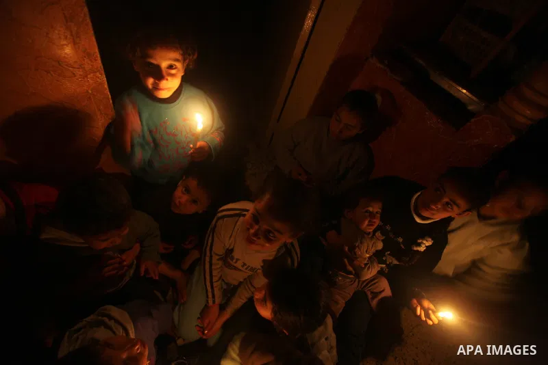 Palestinian children sit at their home during a power cut at the Shati refugee camp in Gaza City on February 11, 2012. The Gaza energy authority announced that if fuel doesn't enter the coastal enclave, the Gaza Strip wi...