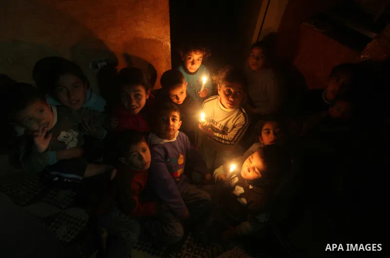 Palestinian children sit at their home during a power cut at the Shati refugee camp in Gaza City on February 11, 2012. The Gaza energy authority announced that if fuel doesn't enter the coastal enclave, the Gaza Strip wi...