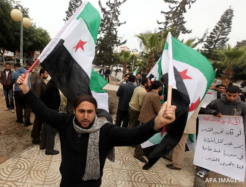 Palestinian demonstrators hold the Syrian national flag during a rally against Syrian President Bashar al-Assad's regime on February 12, 2012 in Gaza City. Photo by Majdi Fathi