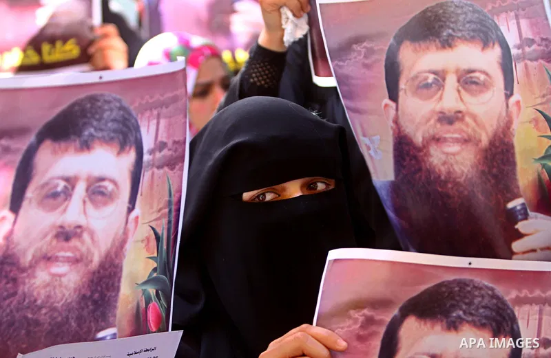 Palestinian women hold posters depicting Palestinian prisoner Khader Adnan, a member of the Islamic Jihad militant group, during a protest in Gaza City, calling for the release of Palestinian prisoners from Israeli jails...