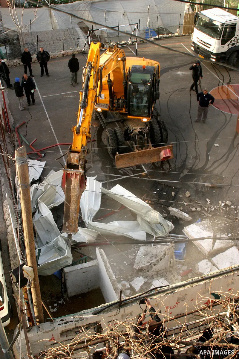Israeli soldiers keep watch as a bulldozer demolishes on February 13, 2012 a Palestinian cbelonging to Jerusalem resident Ahmad al-Baghdadi that was built without the municipality's permission in the holy city's Arab nei...