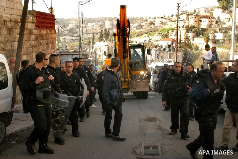 Israeli soldiers keep watch as a bulldozer demolishes on February 13, 2012 a Palestinian cbelonging to Jerusalem resident Ahmad al-Baghdadi that was built without the municipality's permission in the holy city's Arab nei...