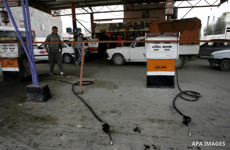 Palestinians wait to fill containers with fuel from a petrol station in Rafah in the southern Gaza Strip, on February 14, 2012, as the Palestinian authority calls on Egypt to provide more fuel. Photo by Abed Rahim Khatib