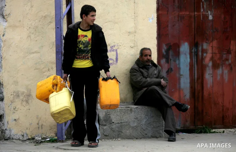Palestinians wait to fill containers with fuel from a petrol station in Rafah in the southern Gaza Strip, on February 14, 2012, as the Palestinian authority calls on Egypt to provide more fuel. Photo by Abed Rahim Khatib