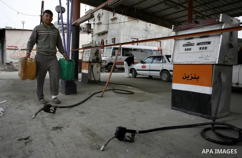 Palestinians wait to fill containers with fuel from a petrol station in Rafah in the southern Gaza Strip, on February 14, 2012, as the Palestinian authority calls on Egypt to provide more fuel. Photo by Abed Rahim Khatib