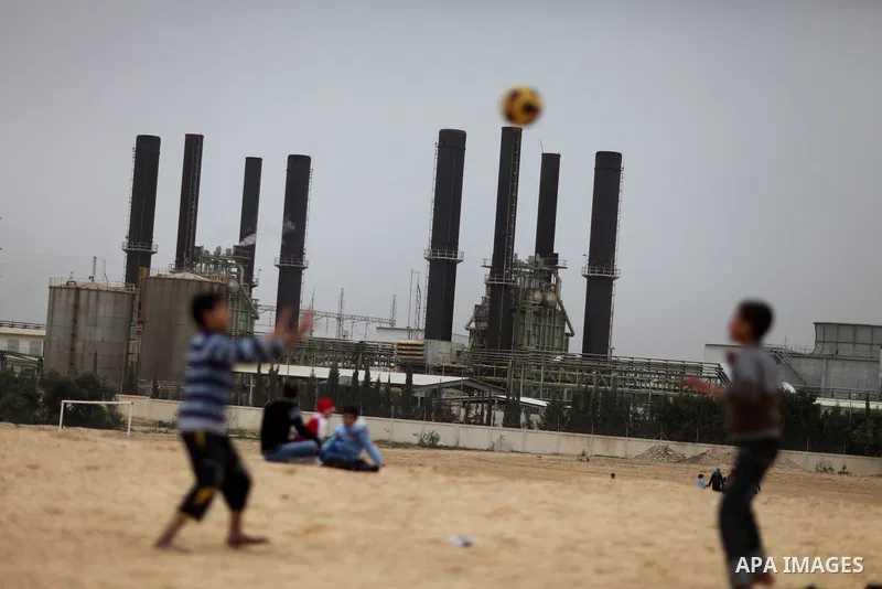 Palestinian boys play football in front of the power plant that generates electricity in Al-Nusirat in the central Gaza Strip, 14 February 2012. The Gaza Energy Authority said that the sole remaining power plant in the G...