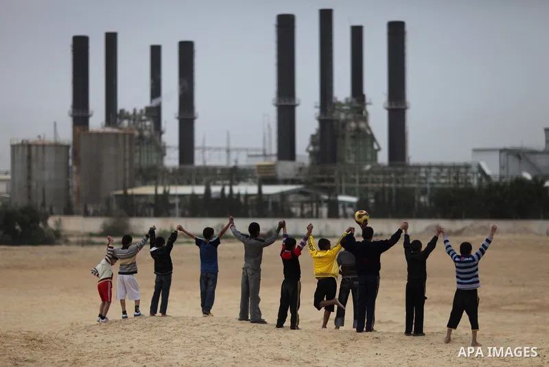 Palestinian boys play football in front of the power plant that generates electricity in Al-Nusirat in the central Gaza Strip, 14 February 2012. The Gaza Energy Authority said that the sole remaining power plant in the G...