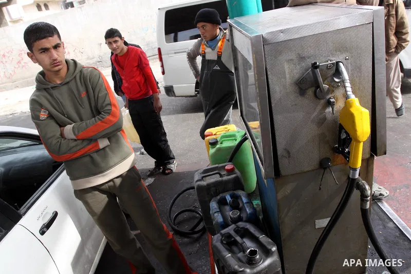 Palestinians wait to fill containers with fuel from a petrol station in Gaza City, on February 15, 2012, as the Palestinian authority calls on Egypt to provide more fuel. Photo by Mohammed Asad