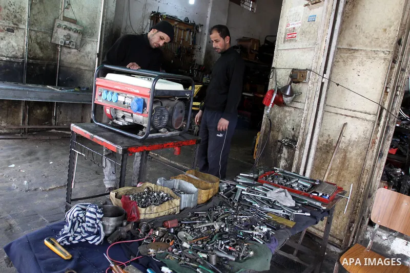 A Palestinian man fixes a generator at a shop in Gaza City, on February 15, 2012. The people of the Gaza Strip use a large number of generators because of the continuing lack of electricity in the Gaza Strip. Photo by Mo...