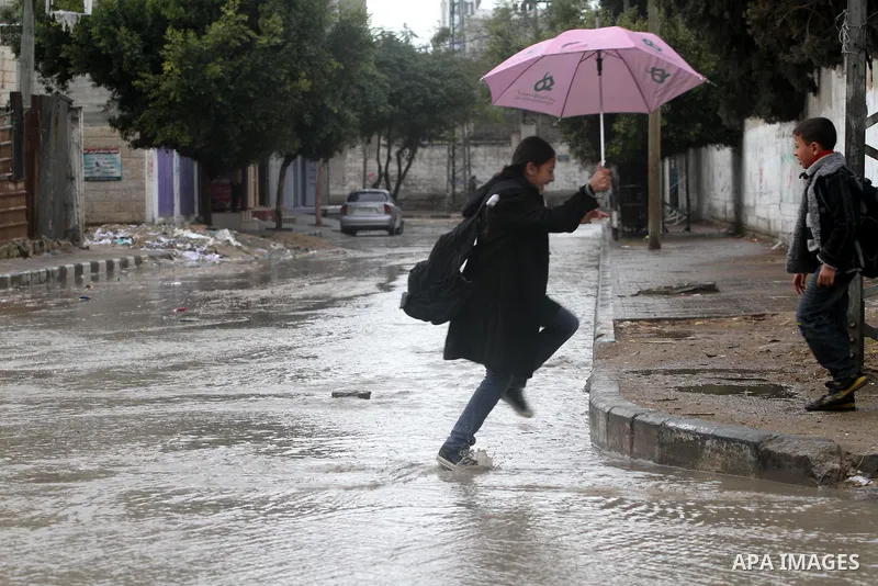 Palestinian students stand in a street during the heavy rain of the winter, in the Gaza City, Feb. 16, 2012. Photo by Mohammed Asad