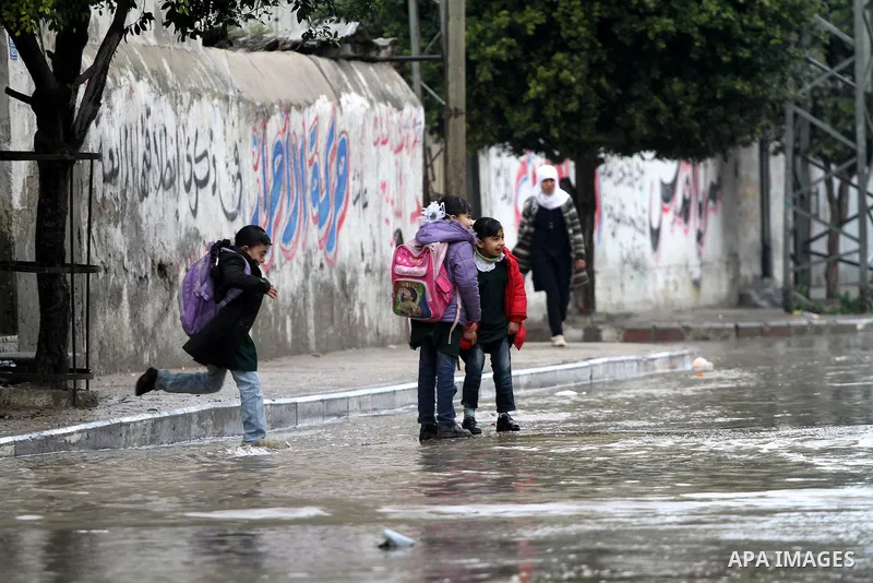 Palestinian students stand in a street during the heavy rain of the winter, in the Gaza City, Feb. 16, 2012. Photo by Mohammed Asad