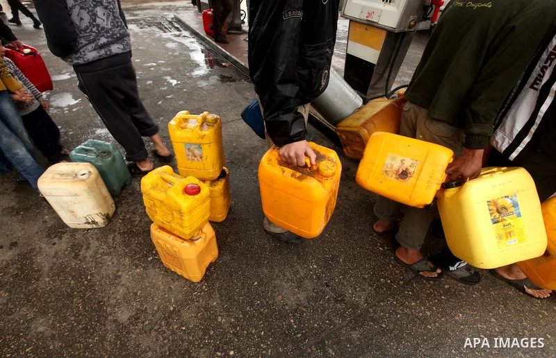 Palestinians fill containers with fuel from a petrol station in the Gaza City on 16 February 2012. Reports state that residents in the Gaza Strip flocked to petrol stations hoping to get a share of the remaining fuel, sa...