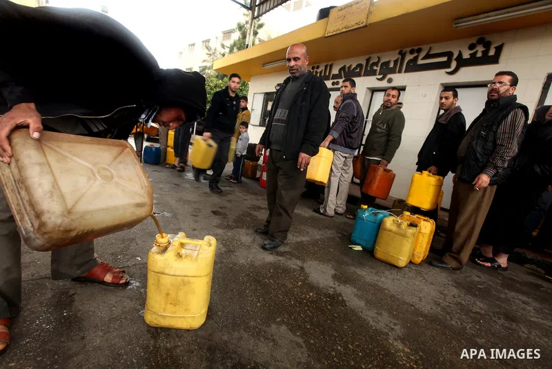 Palestinians fill containers with fuel from a petrol station in the Gaza City on 16 February 2012. Reports state that residents in the Gaza Strip flocked to petrol stations hoping to get a share of the remaining fuel, sa...