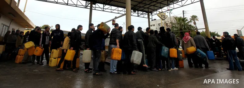 Palestinians fill containers with fuel from a petrol station in the Gaza City on 16 February 2012. Reports state that residents in the Gaza Strip flocked to petrol stations hoping to get a share of the remaining fuel, sa...