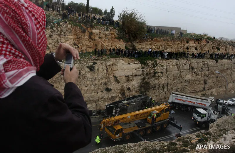 Israeli and Palestinian rescue workers stand with onlookers at the scene of an accident near the Qalandiya checkpoint outside the West Bank city of Ramallah February 16, 2012. At least five Palestinian children were kill...