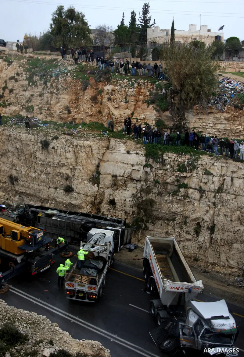 Israeli and Palestinian rescue workers stand with onlookers at the scene of an accident near the Qalandiya checkpoint outside the West Bank city of Ramallah February 16, 2012. At least five Palestinian children were kill...